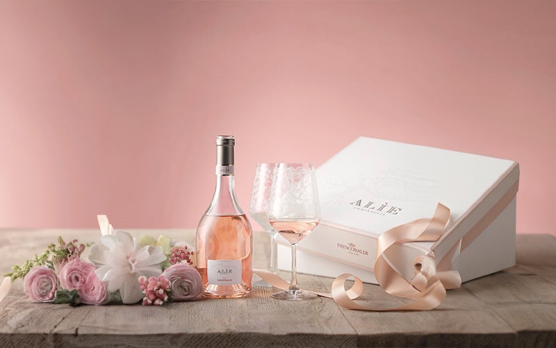 Roze roos met een fles rosé ernaast