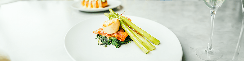 Bord gevuld met recept met asperges, bacon, coquille