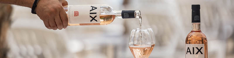 Drie flessen AIX Rose waar 1 glas wordt ingeschonken