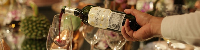 Grote tafel met eten waar een glas wijngeschonken wordt