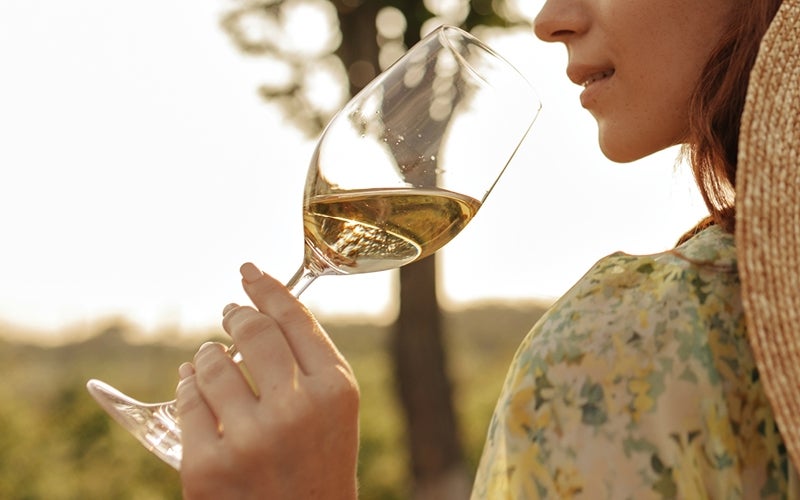 Vrouw houdt glas witte wijn vast om aan te ruiken