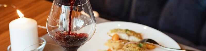 Glas waar rode wijn wordt ingeschonken