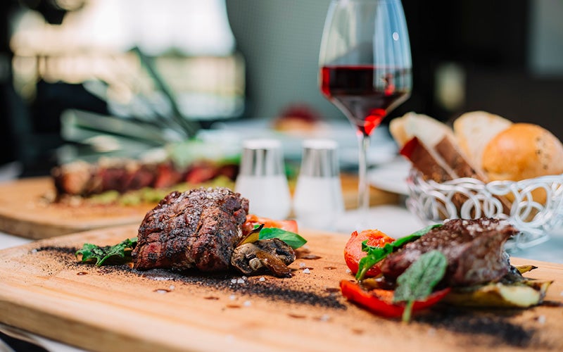 Stuk vlees van de barbecue op tafel met glazen rode wijn