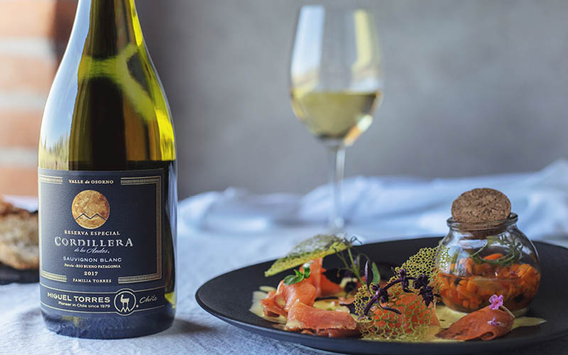 Bord met zalm, glas witte wijn en een fles Cordillera